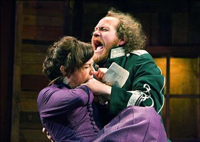 Kate in a purple dress, bites Petruchio's hand